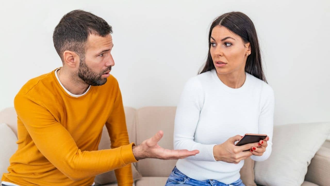 Man pointing to a woman with a smartphone.