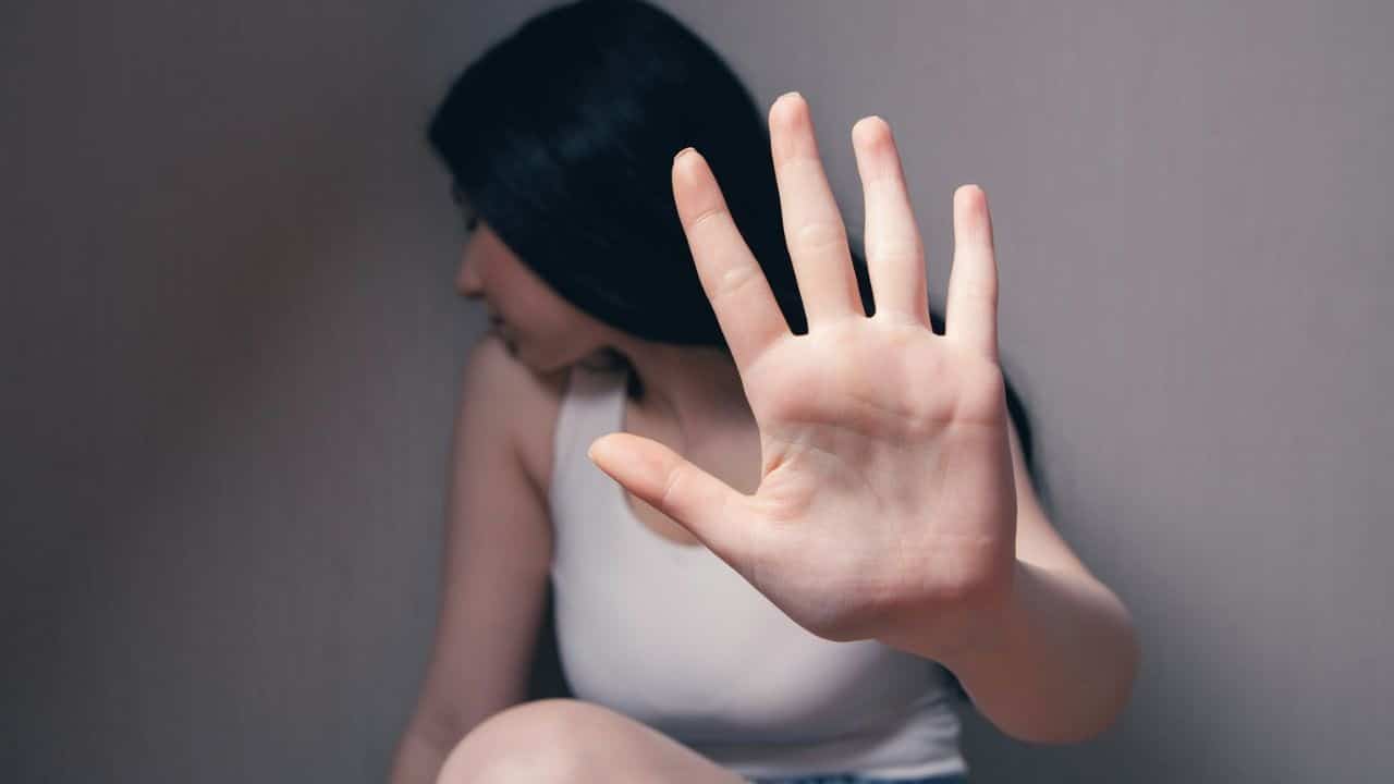 A woman is raising her hands to her ears, blocking her ears from camera view.