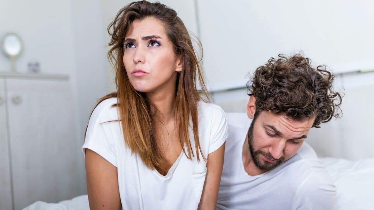 A disappointed woman looks away from a man who is looking down.