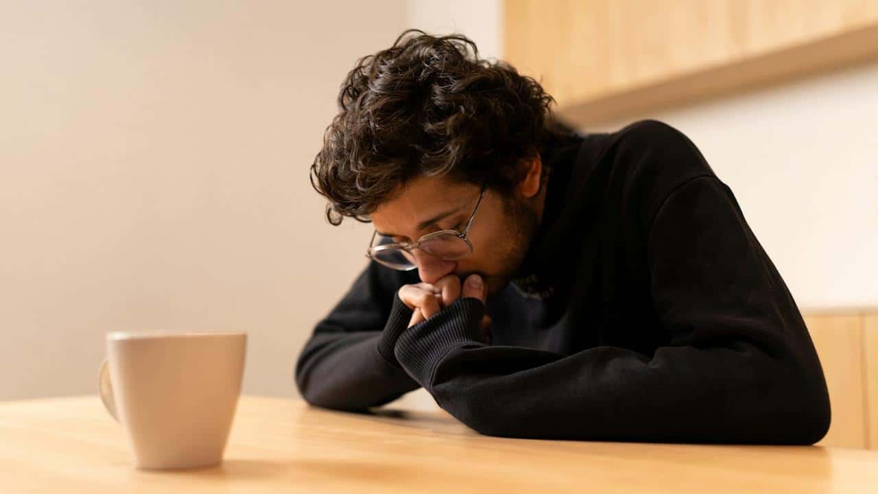 A man sitting at a table with a coffee cup in front of him.