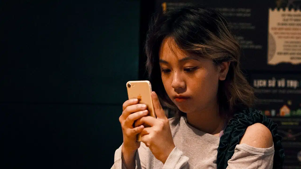A sad woman is using a phone outdoors.