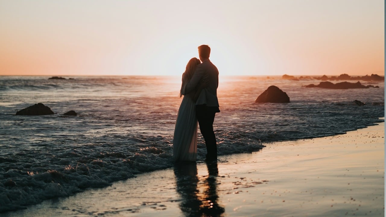 A couple standing together on the beach.