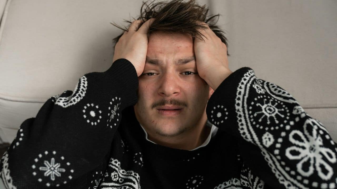 A man with his hands on his head in distress.