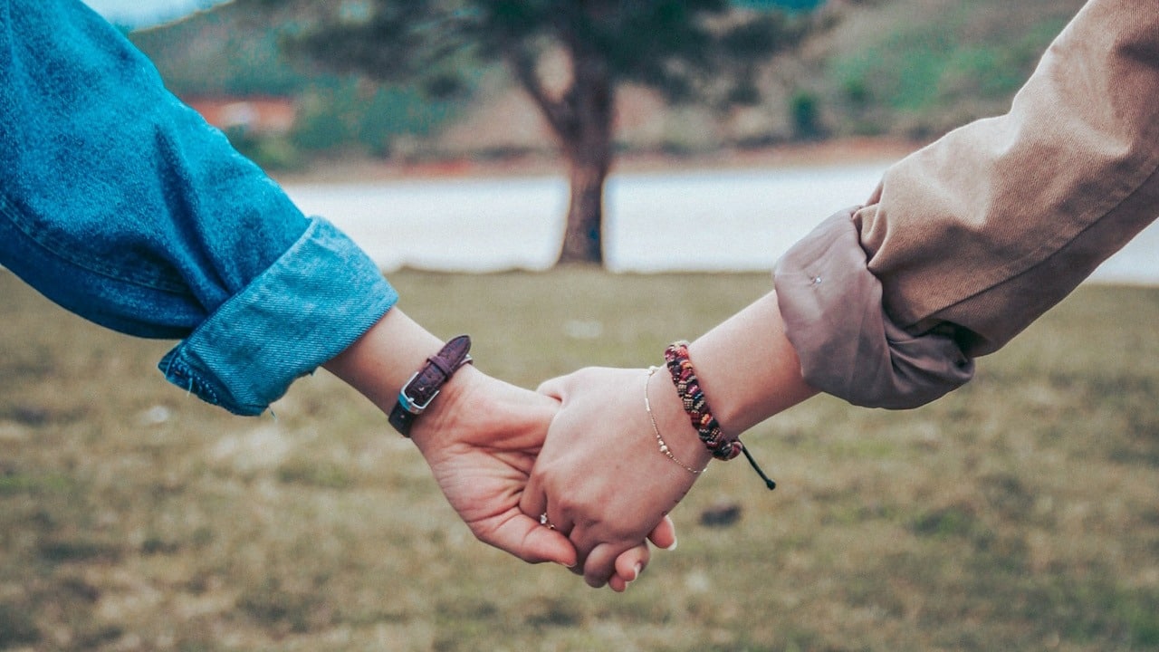A couple holding hands while standing in front of a tree.