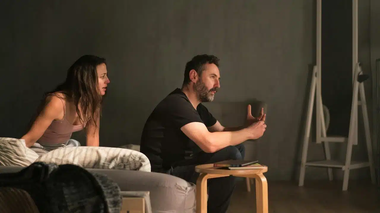 A woman complaining to her husband while he is sitting silent.