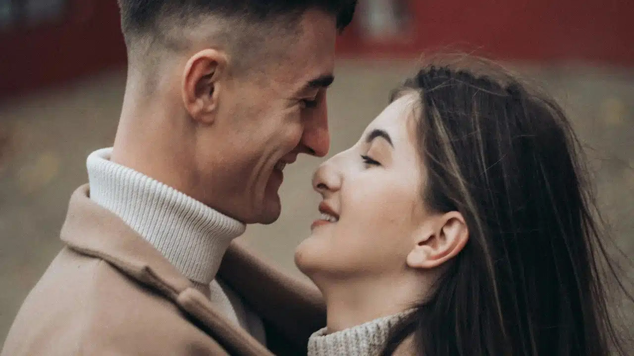 A man and woman smiling at each other and about to kiss.