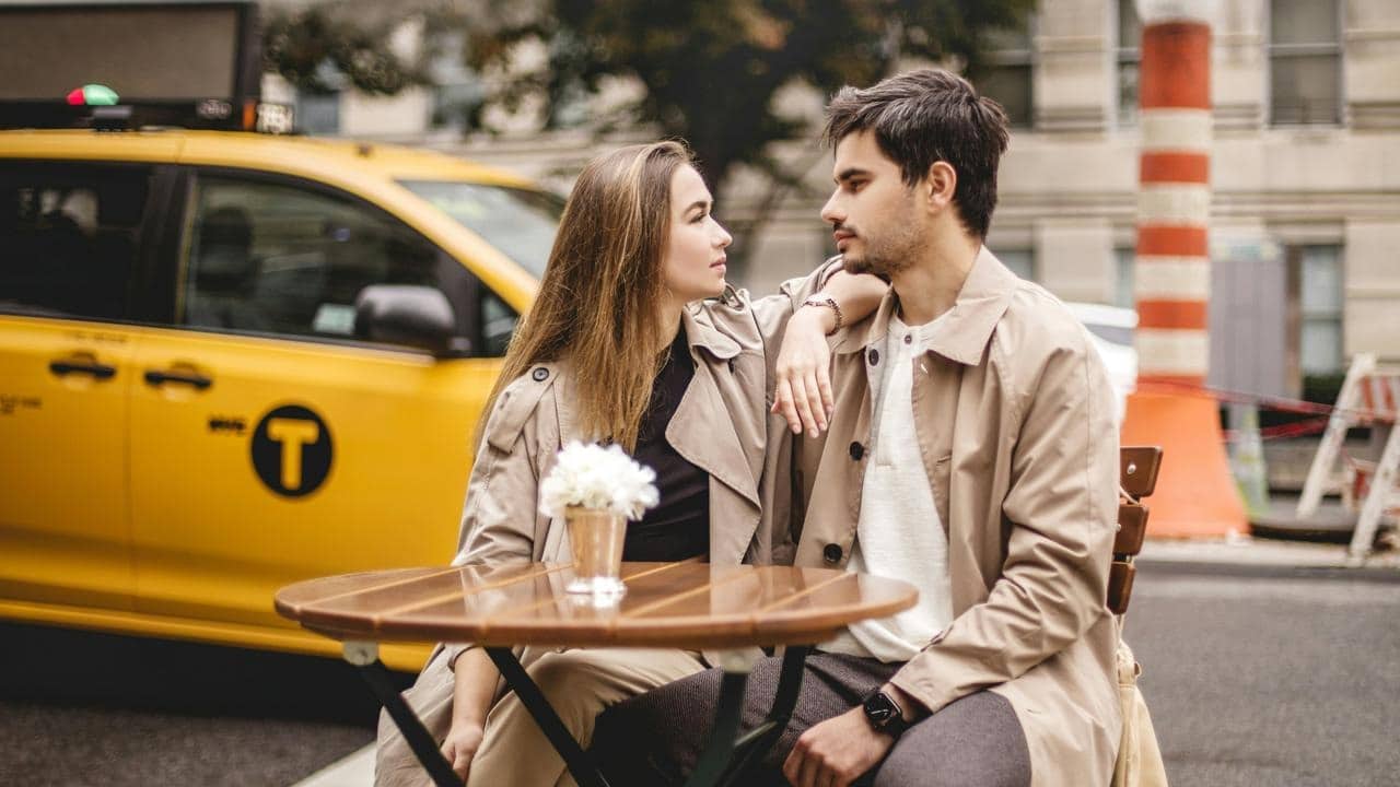 A couple sitting closely at a small outdoor café table on a city street.