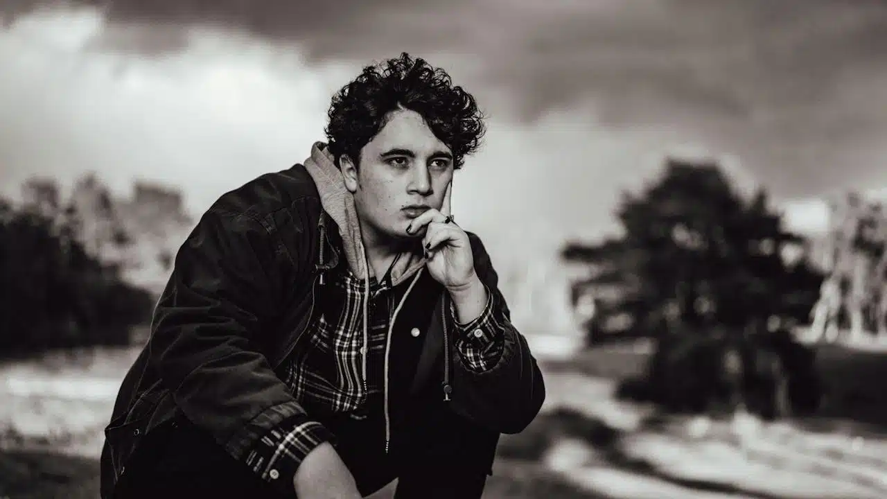 A man sitting and thinking about something while holding his hand up to his face and staring in the distance.