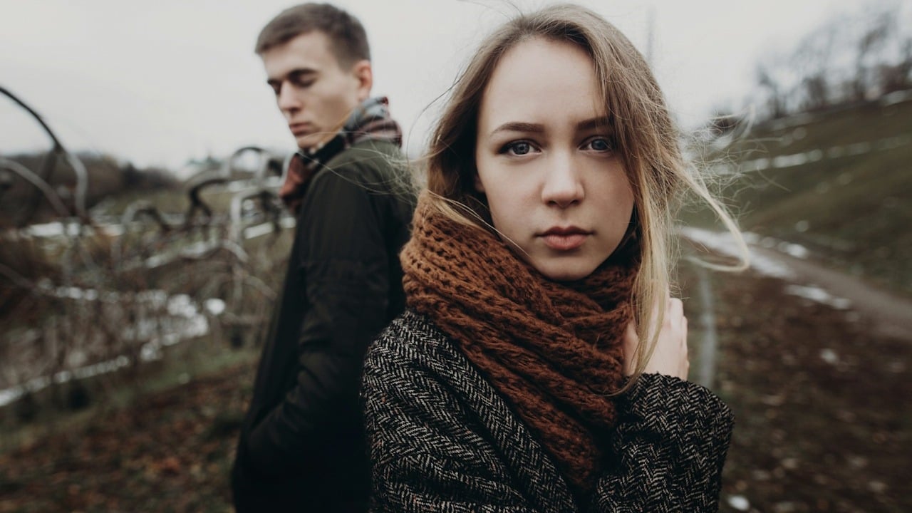 A couple standing in a windy autumn park.