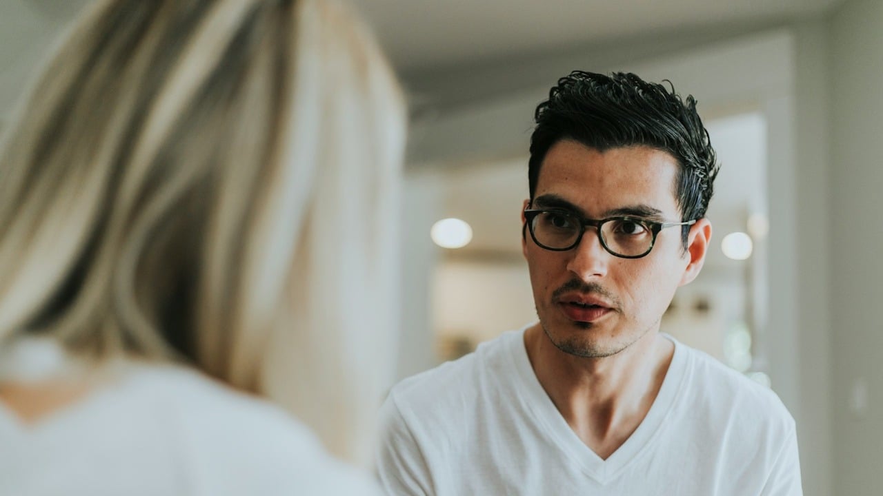 A man looking at a woman sitting in front of him.