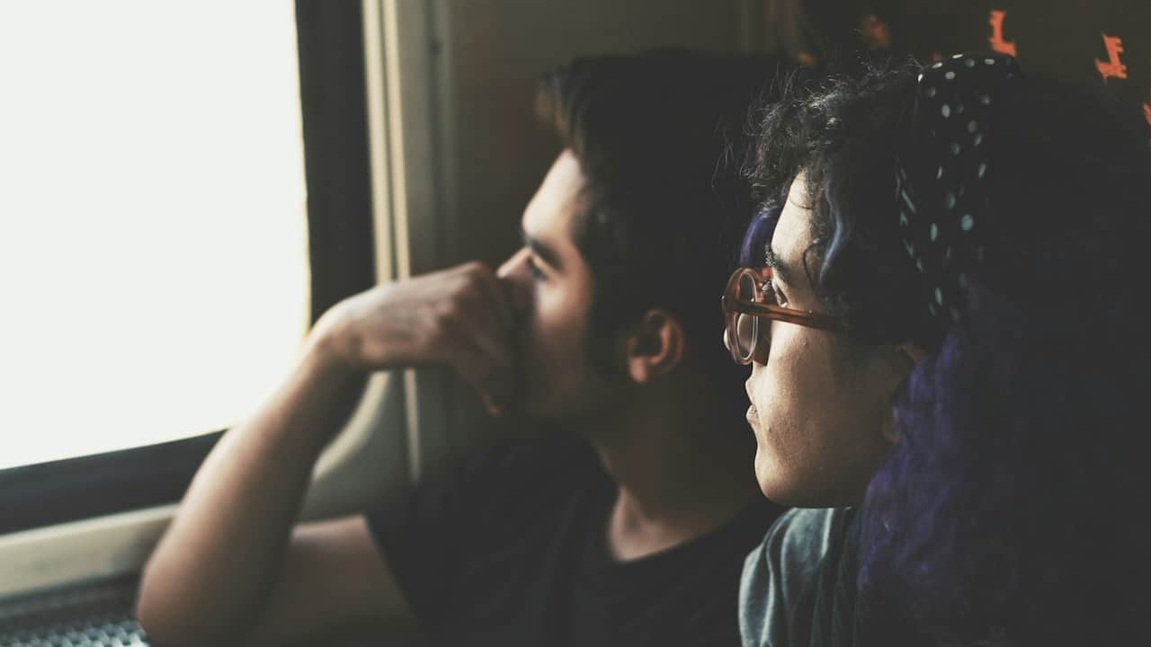 A man and a woman sitting together looking out of the window of the train.