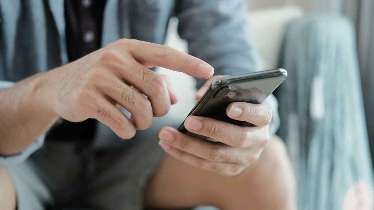 A woman looks at her phone while a man sits nearby looking in another direction.