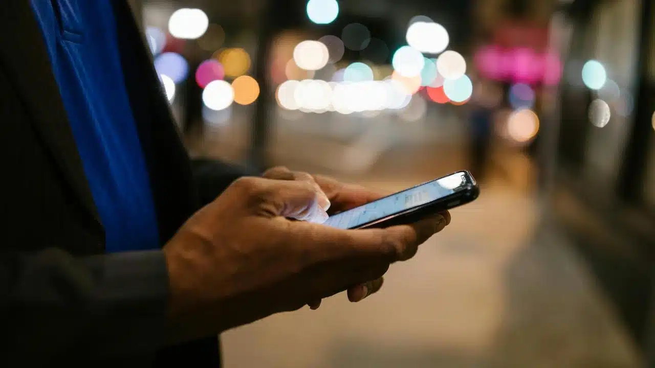 A person using a smartphone on a city street at night.