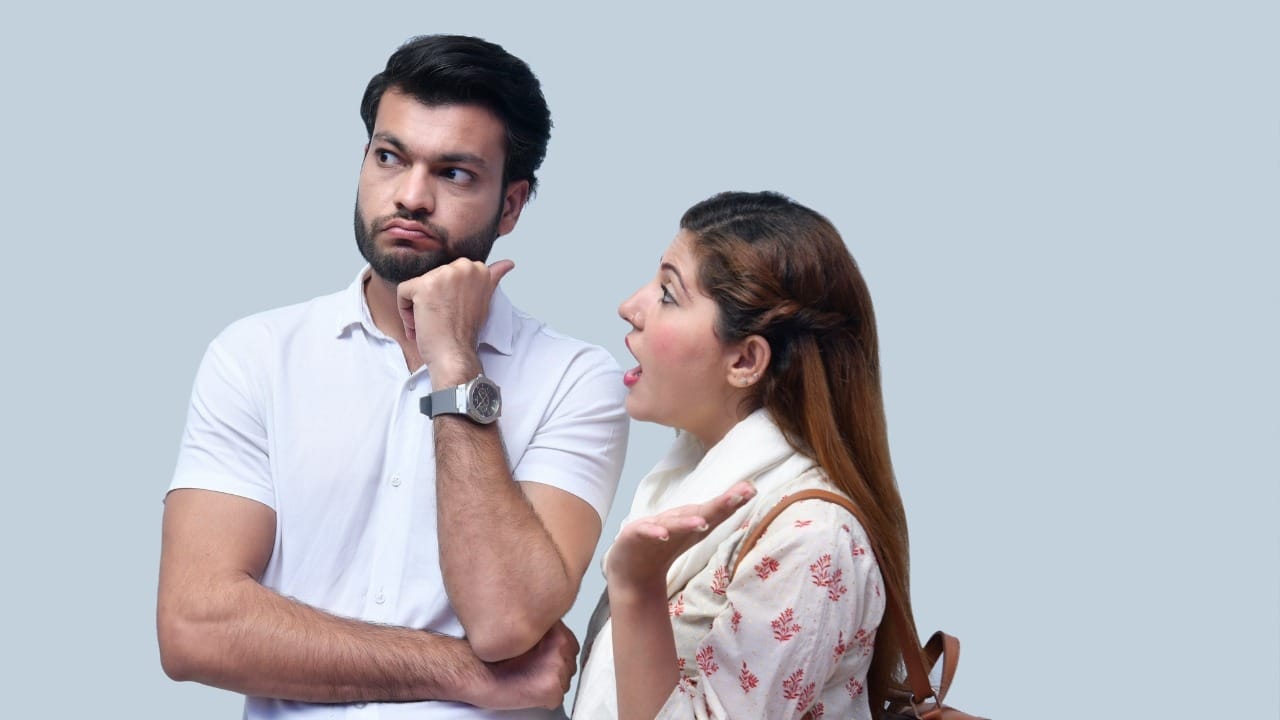 A woman speaks with an open mouth toward a man who is looking away thoughtfully.