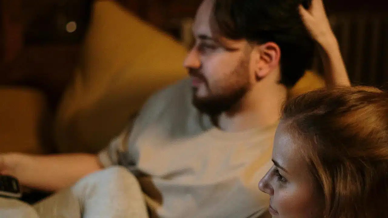 A couple sitting together and watching television at home.