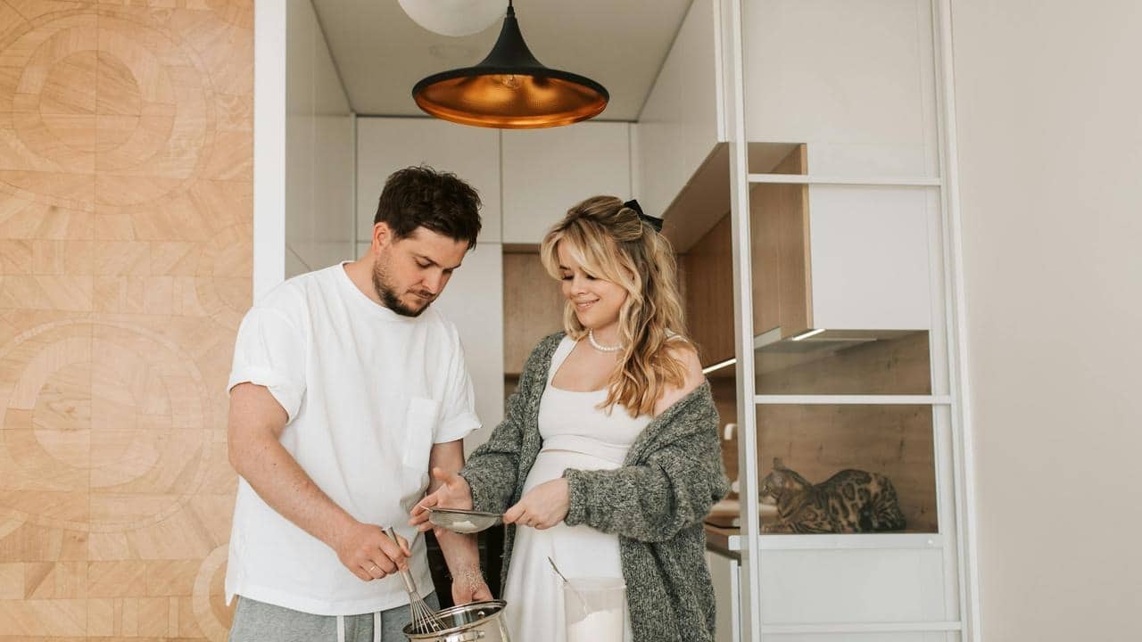 A couple cooking together in a bright kitchen.
