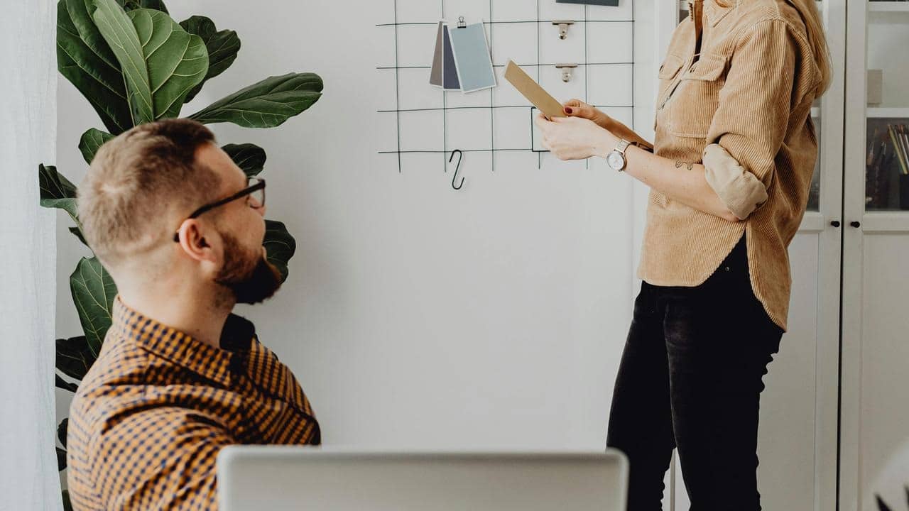 A woman showing color samples to a man in an office.