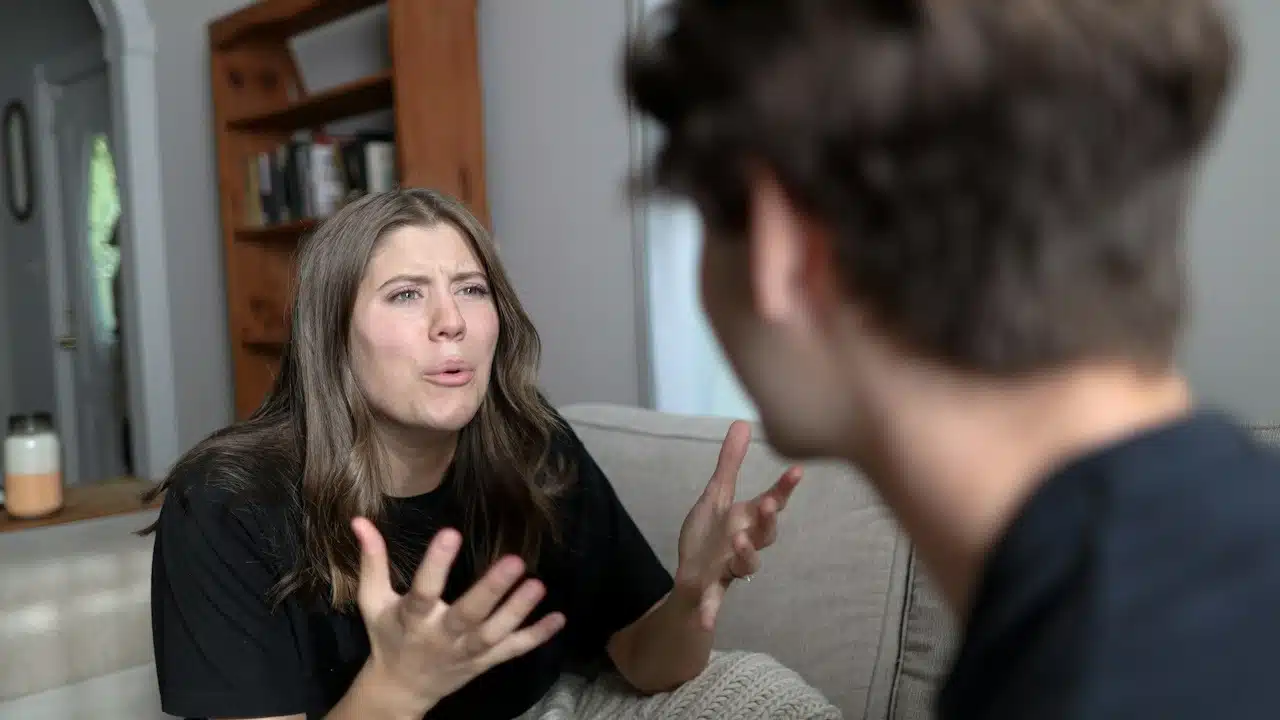A woman arguing with a man as they sit on a couch.