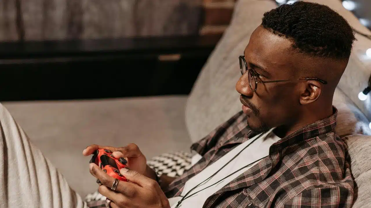 A man relaxing on a couch while playing a video game with a controller.