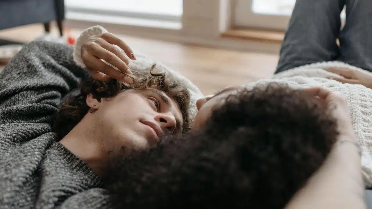A couple lying close together, gazing at each other affectionately.