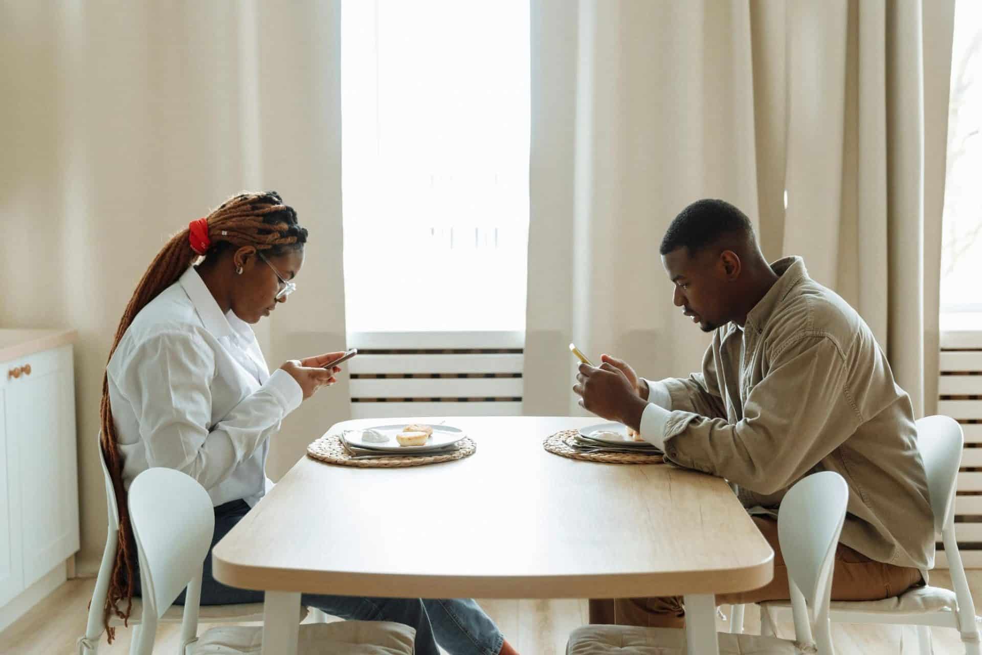 A couple sitting at opposite ends of a table.