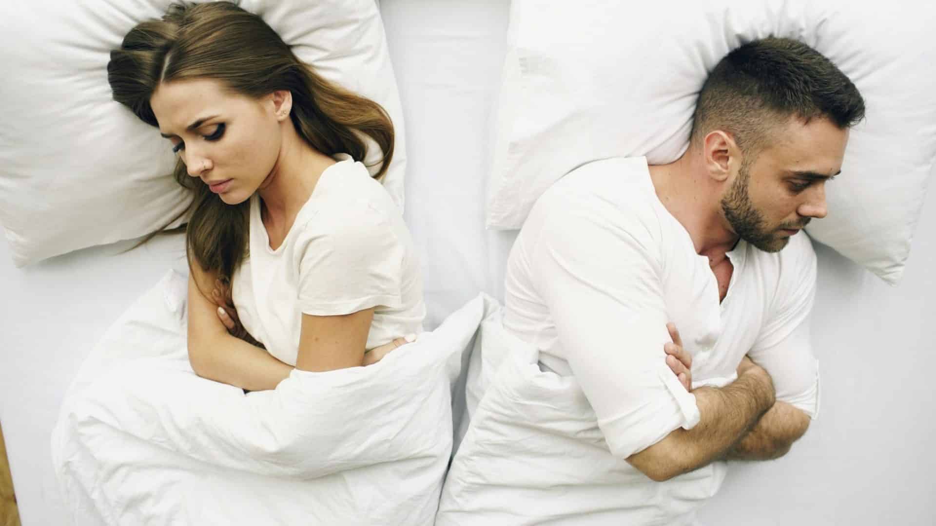 A couple in bed facing away from each other.