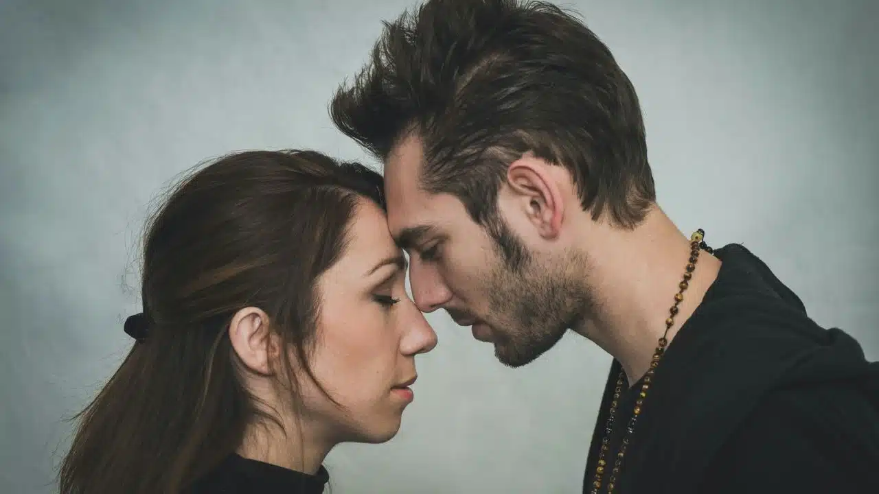 A man and woman lean toward each other with their eyes closed and foreheads touching.