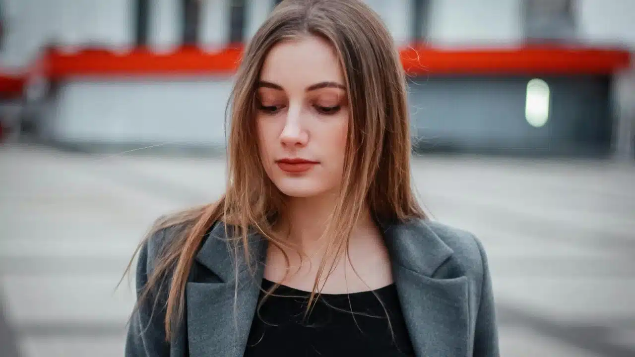 A woman looking down while standing outdoors.