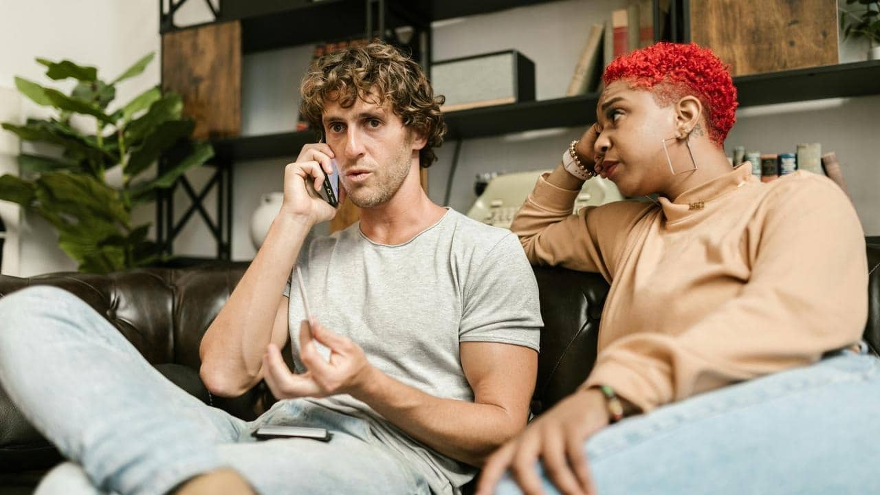 A man talking on his phone while a woman beside him looks on with concern.