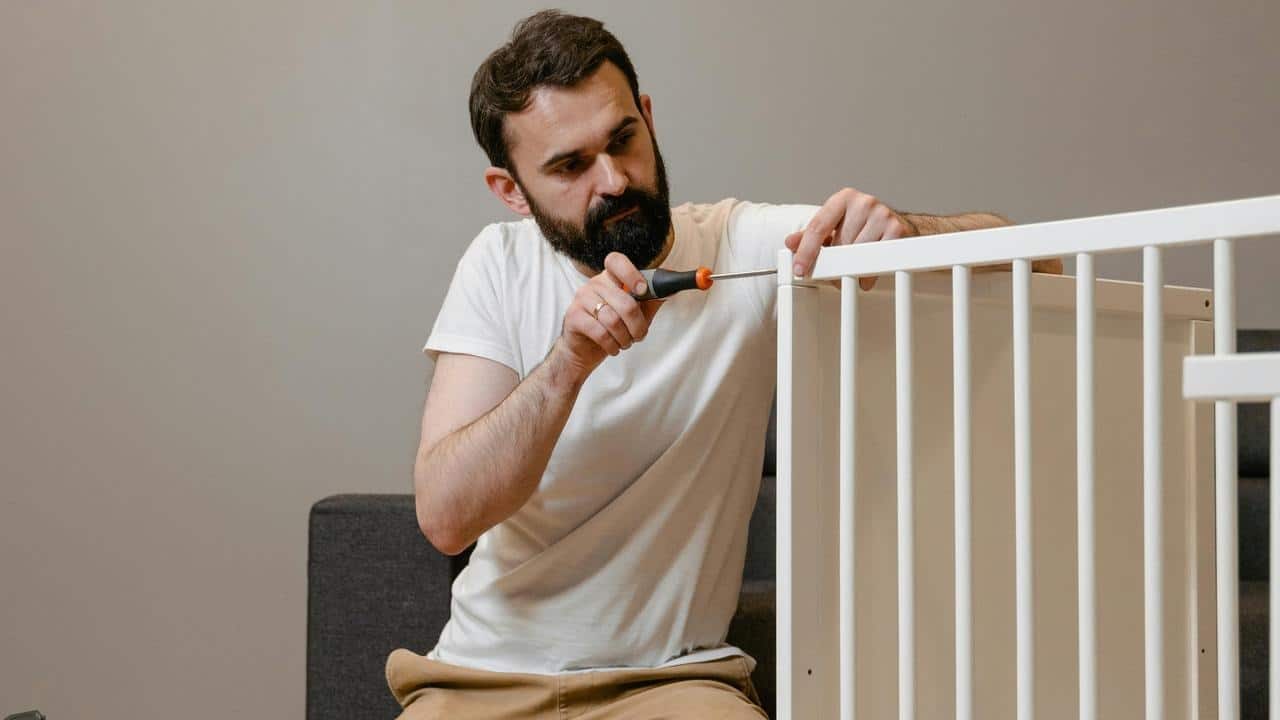 A man using a screwdriver to assemble a piece of furniture.