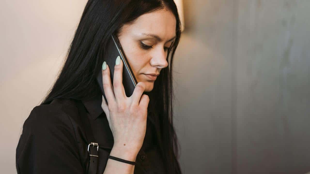 A woman holding a phone to her ear, listening attentively.