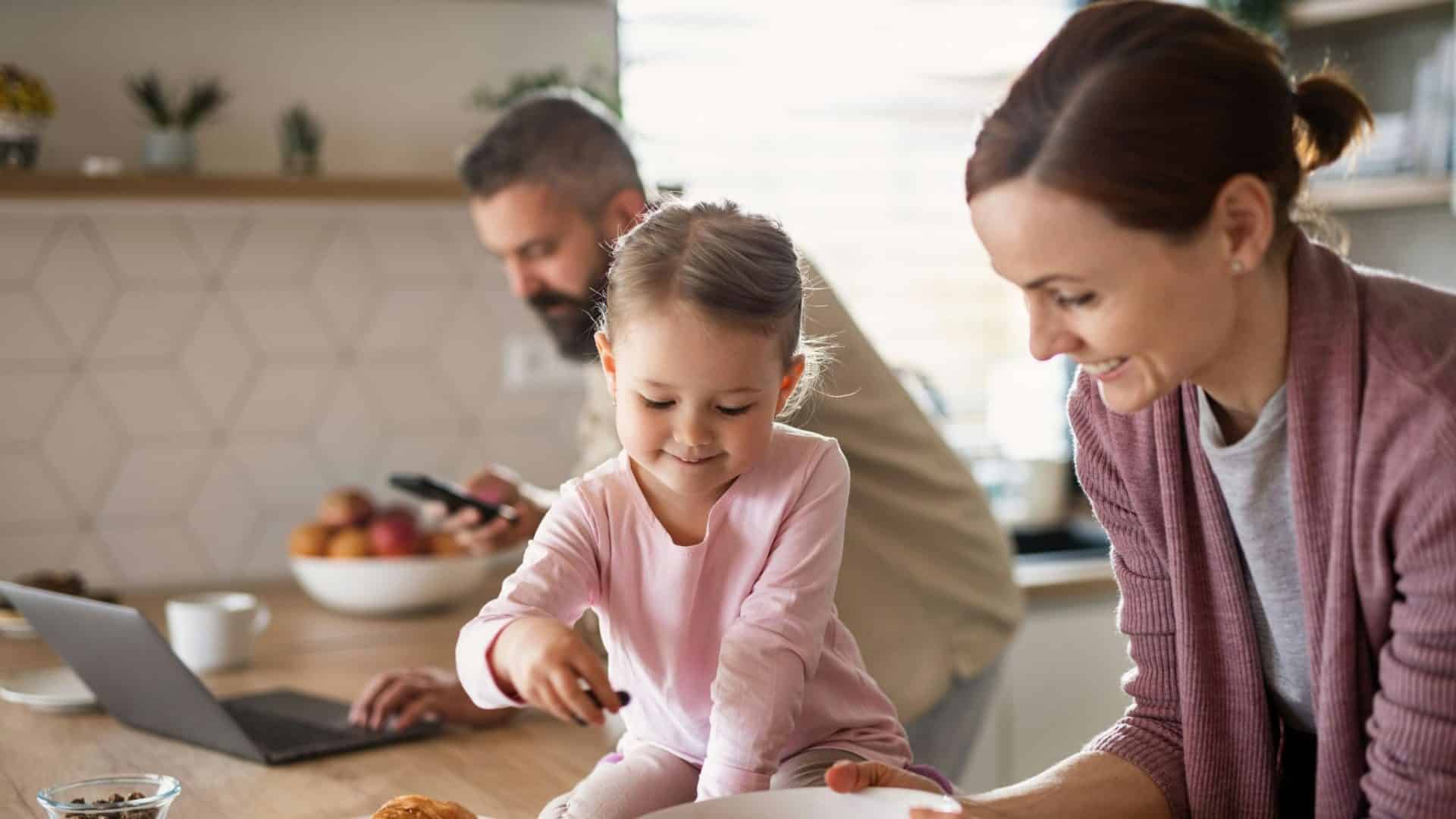 A man busy working and a woman busy with toddler