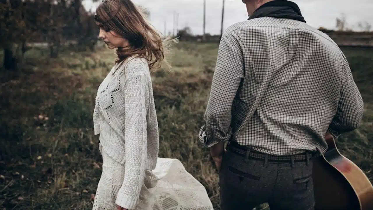 A woman walking away from a man on a quiet street, symbolizing separation