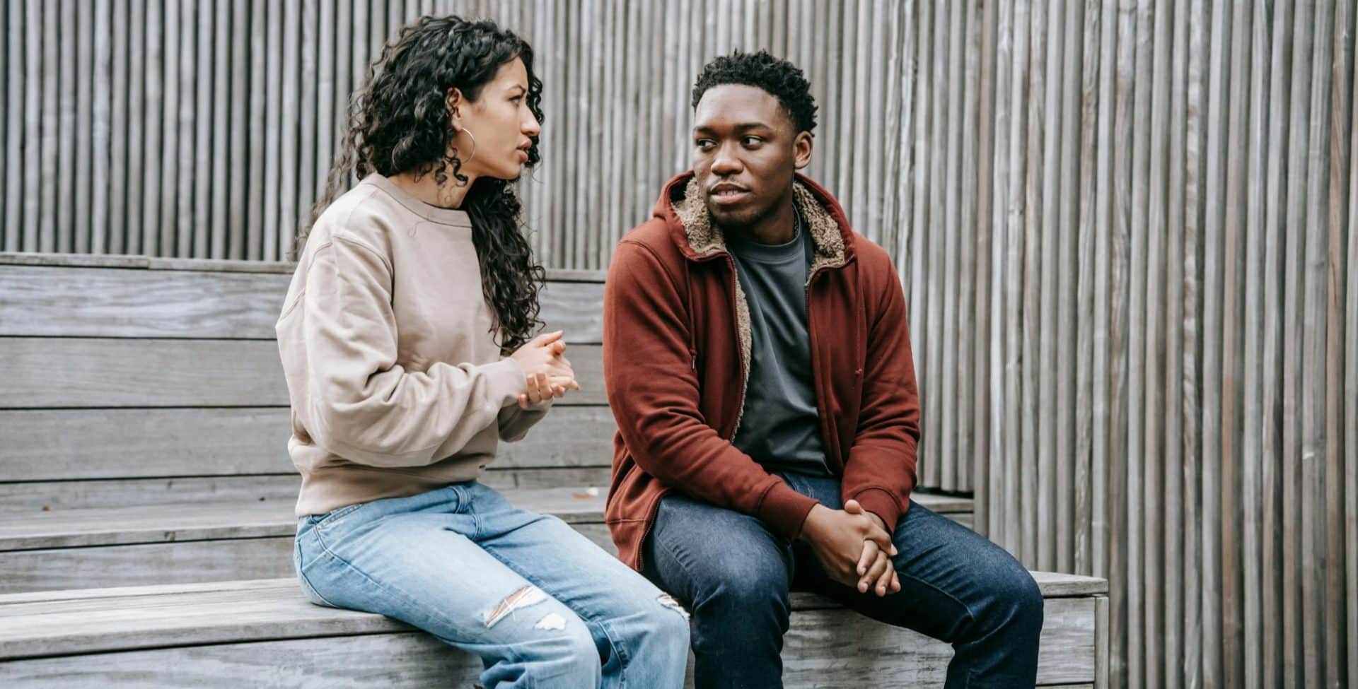 A woman speaking carefully while a man listens without engagement.