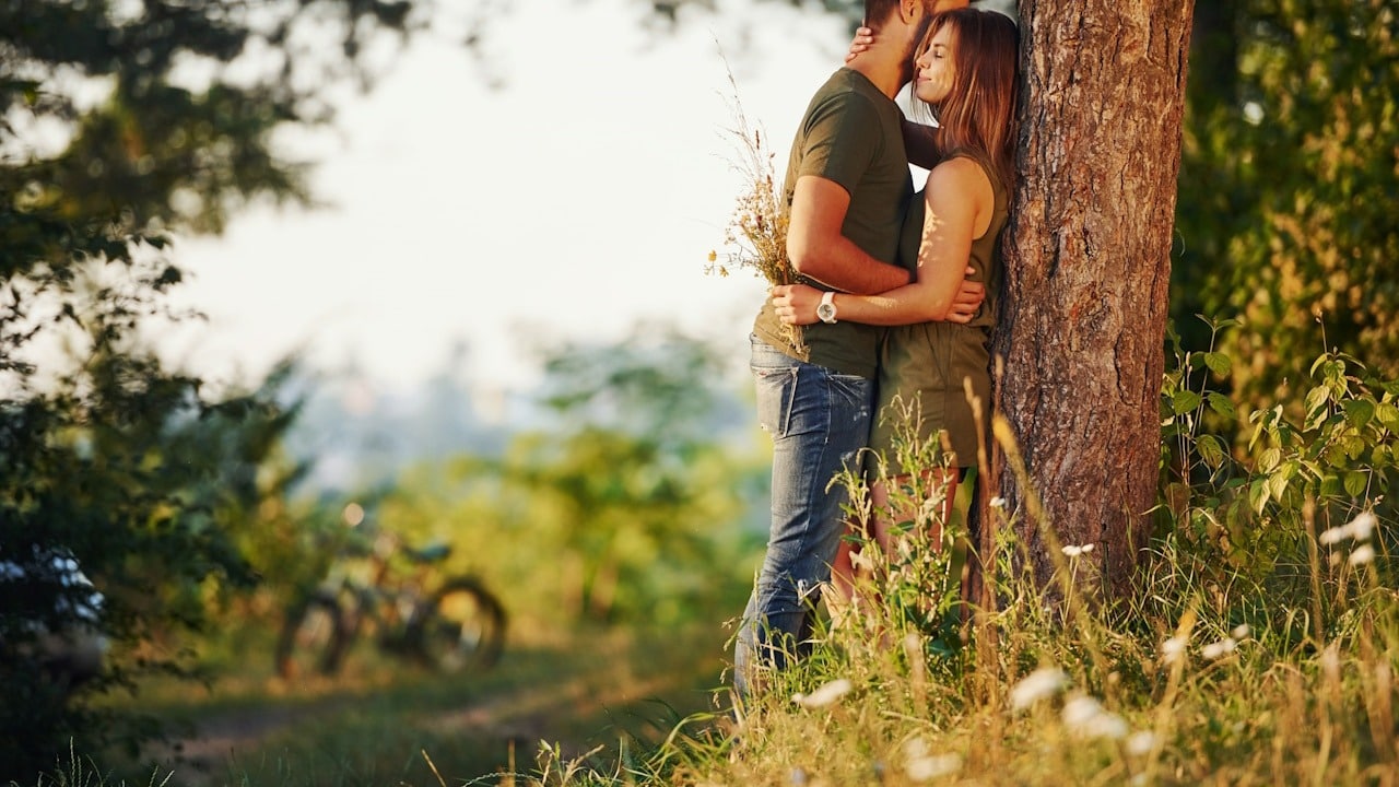 A couple hugging each other in a forest.