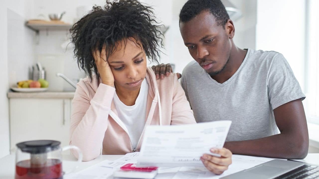 A man and woman look at a paper document together with serious expressions at a table.