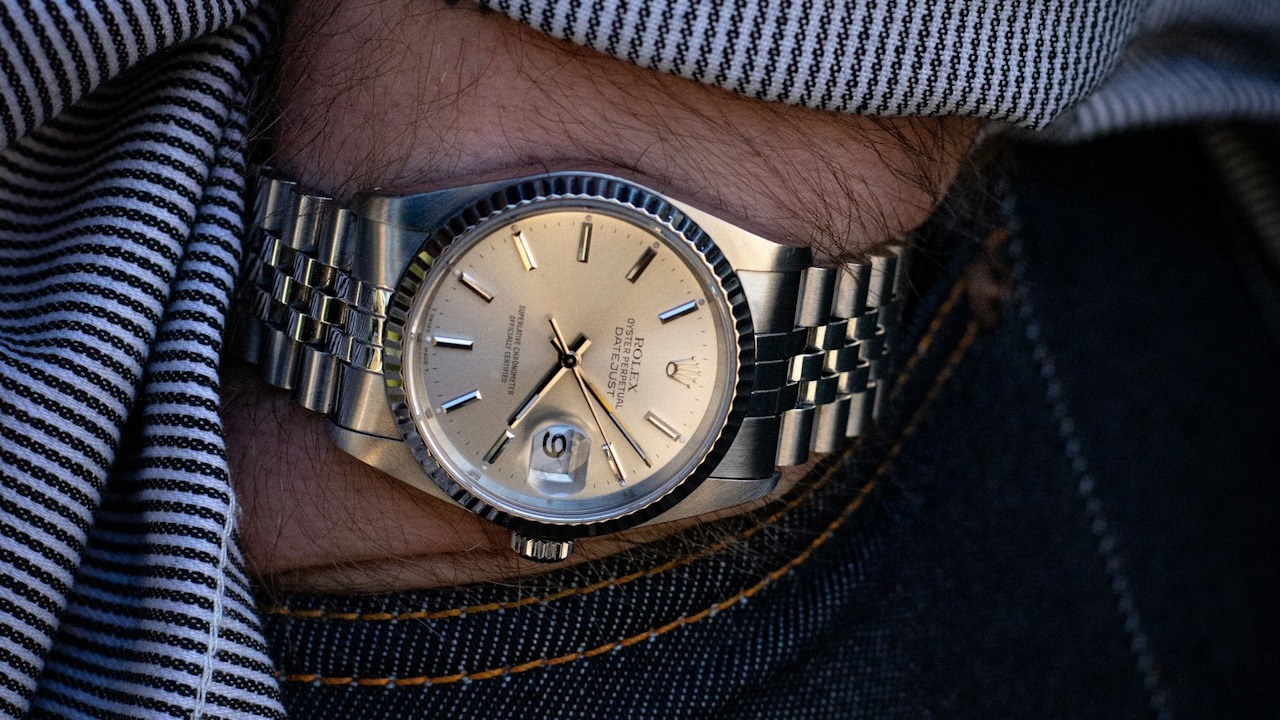 A man wearing a wristwatch while inserting his hand in his jeans pocket.