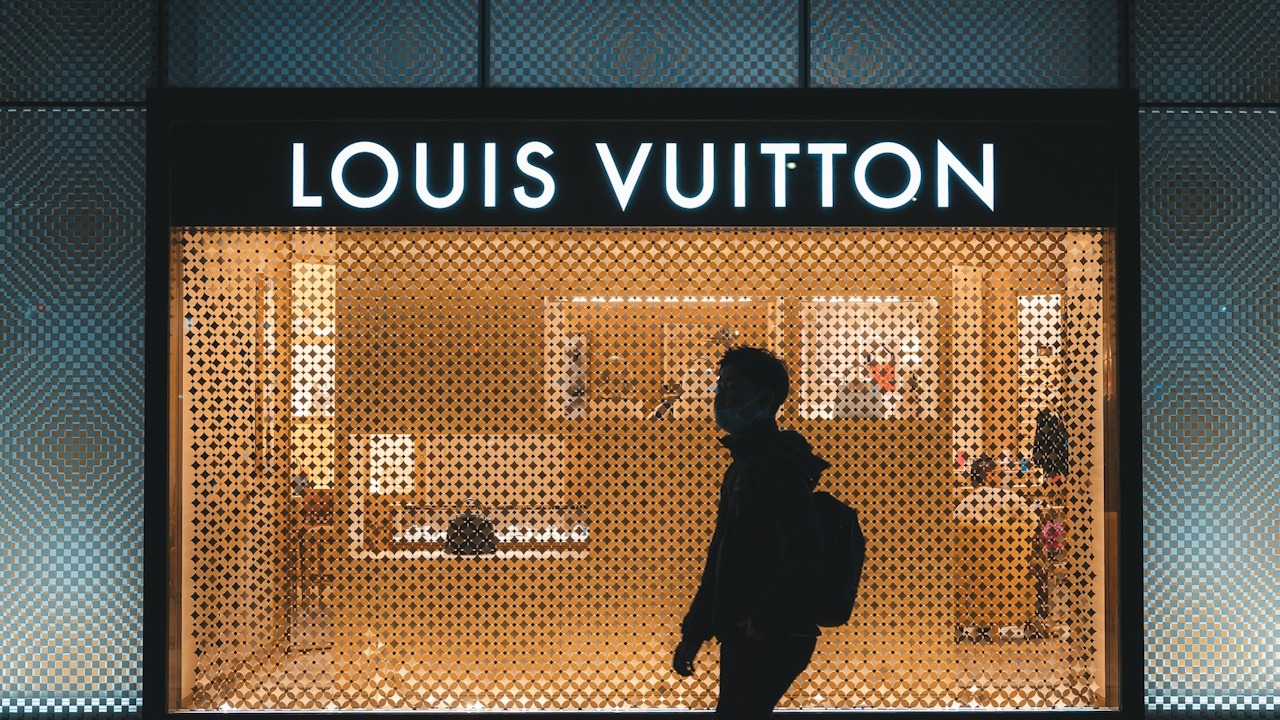 A man walking by a Louis Vuitton store.