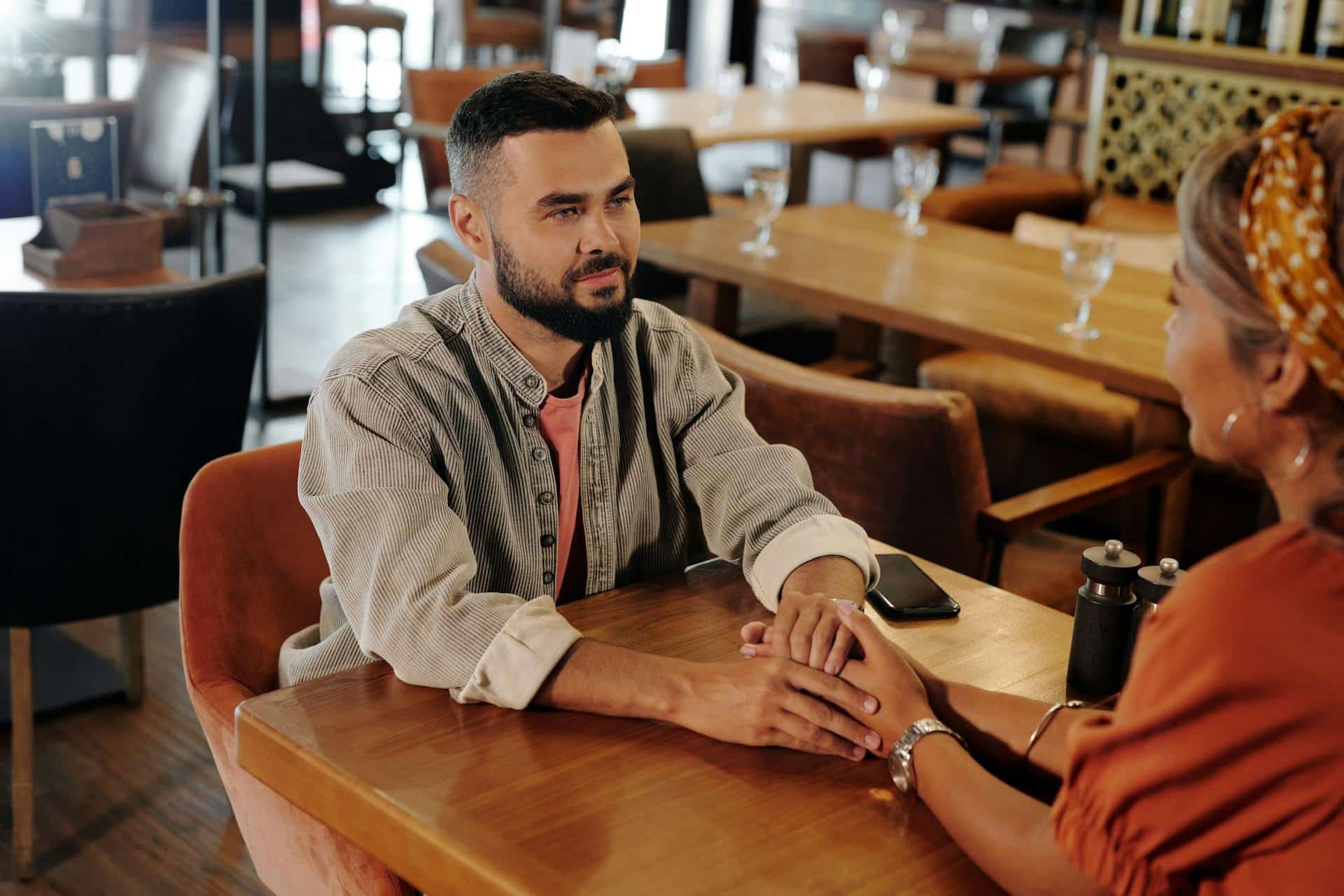 The couple inside the restaurant is holding hands.