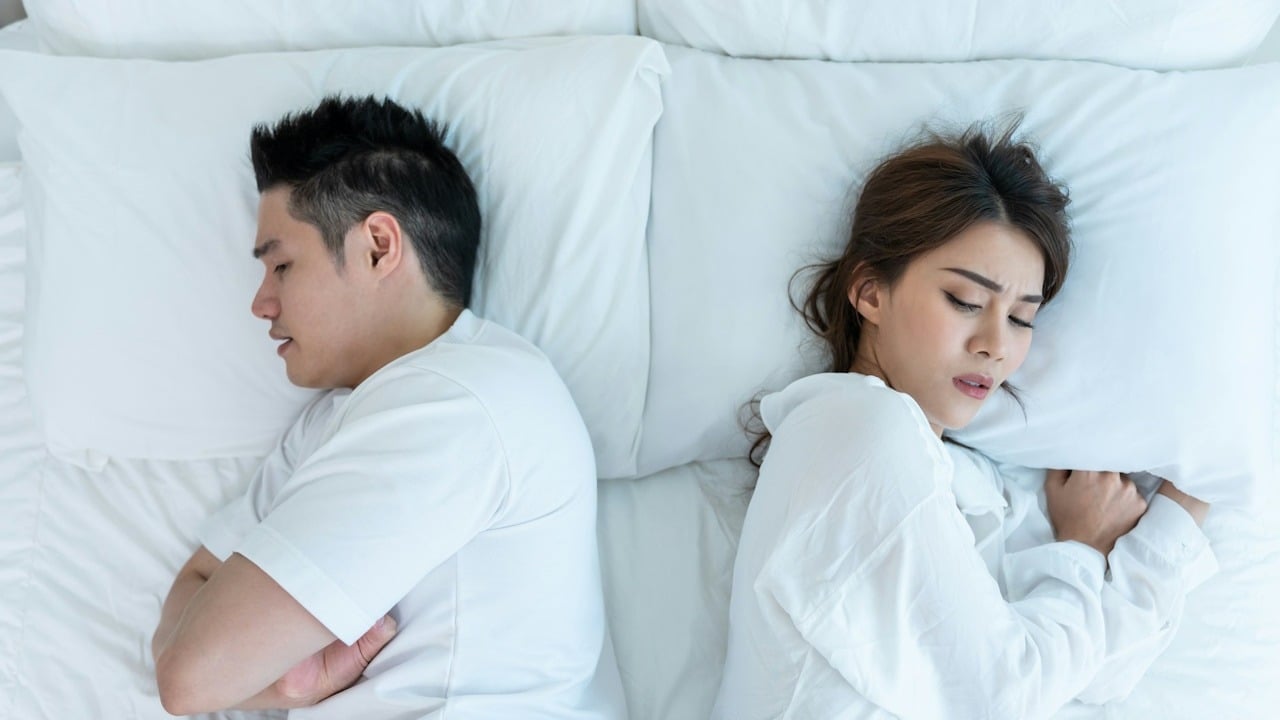 A couple lying in bed with their backs to each other and refusing to talk.