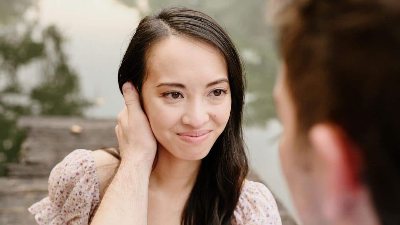 A man holding a smiling woman’s cheek.