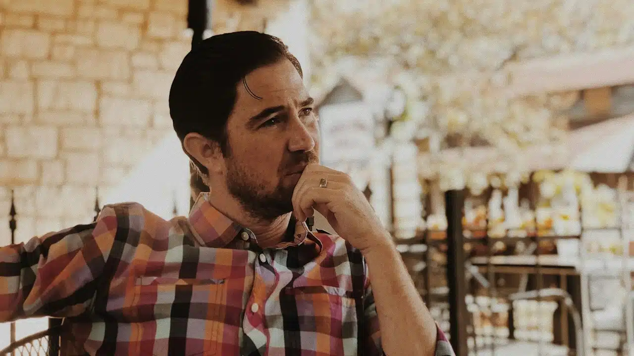 A bearded man lost in thought.