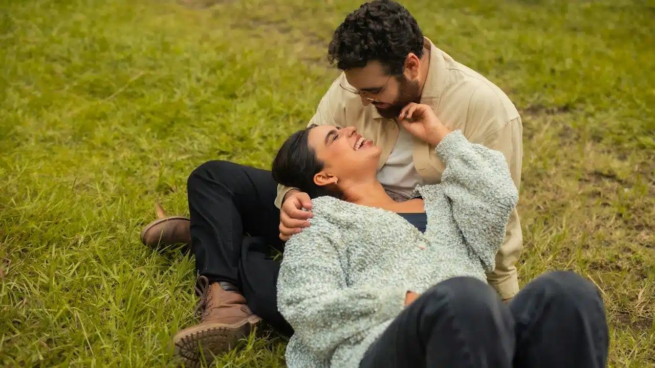 A couple sitting on separate ends of a bed facing away from each other