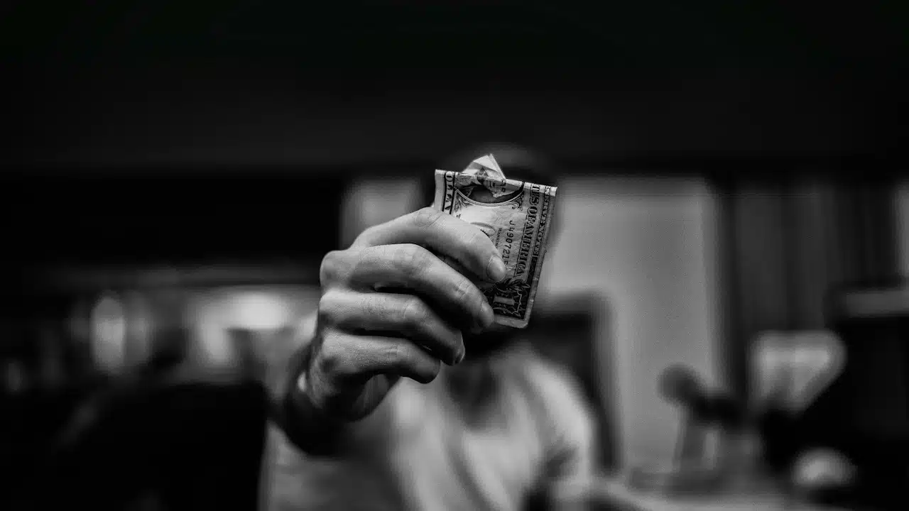 A man holding up a dollar note.