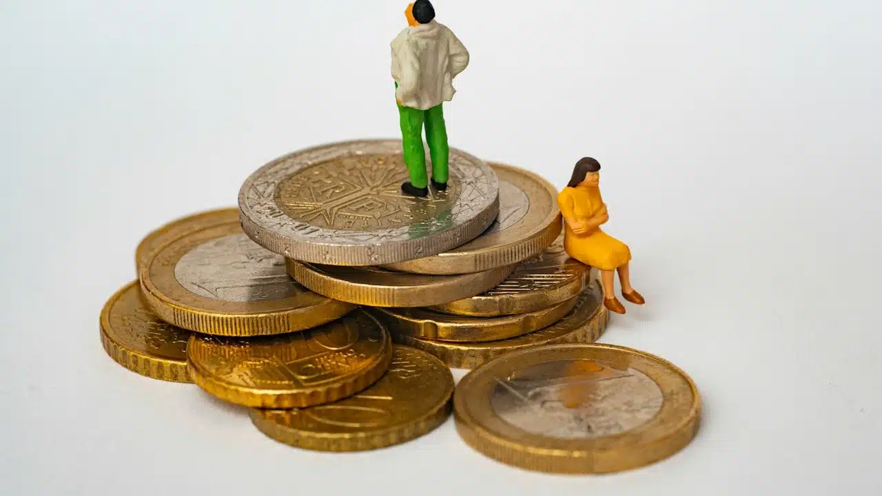 A man standing on the stack of gold and lady sitting beneath it