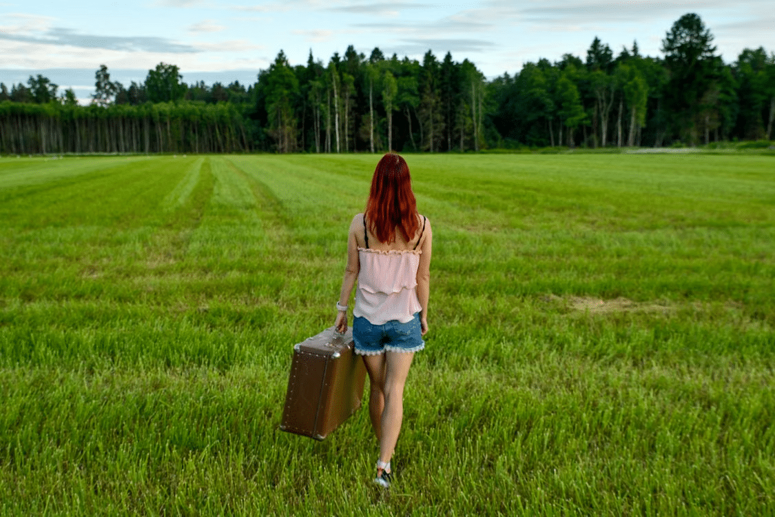 Woman with a suitcase symbolizing walking to the next phase in a life with a suitcase.