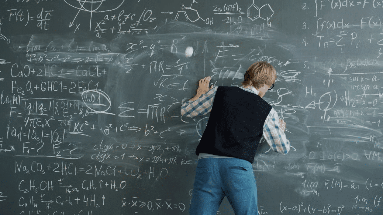 A man focused on writing equations on the board.