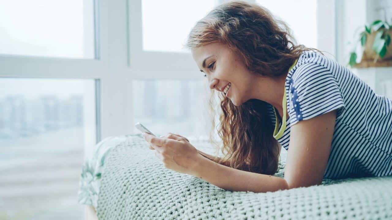 A woman smiling while texting.
