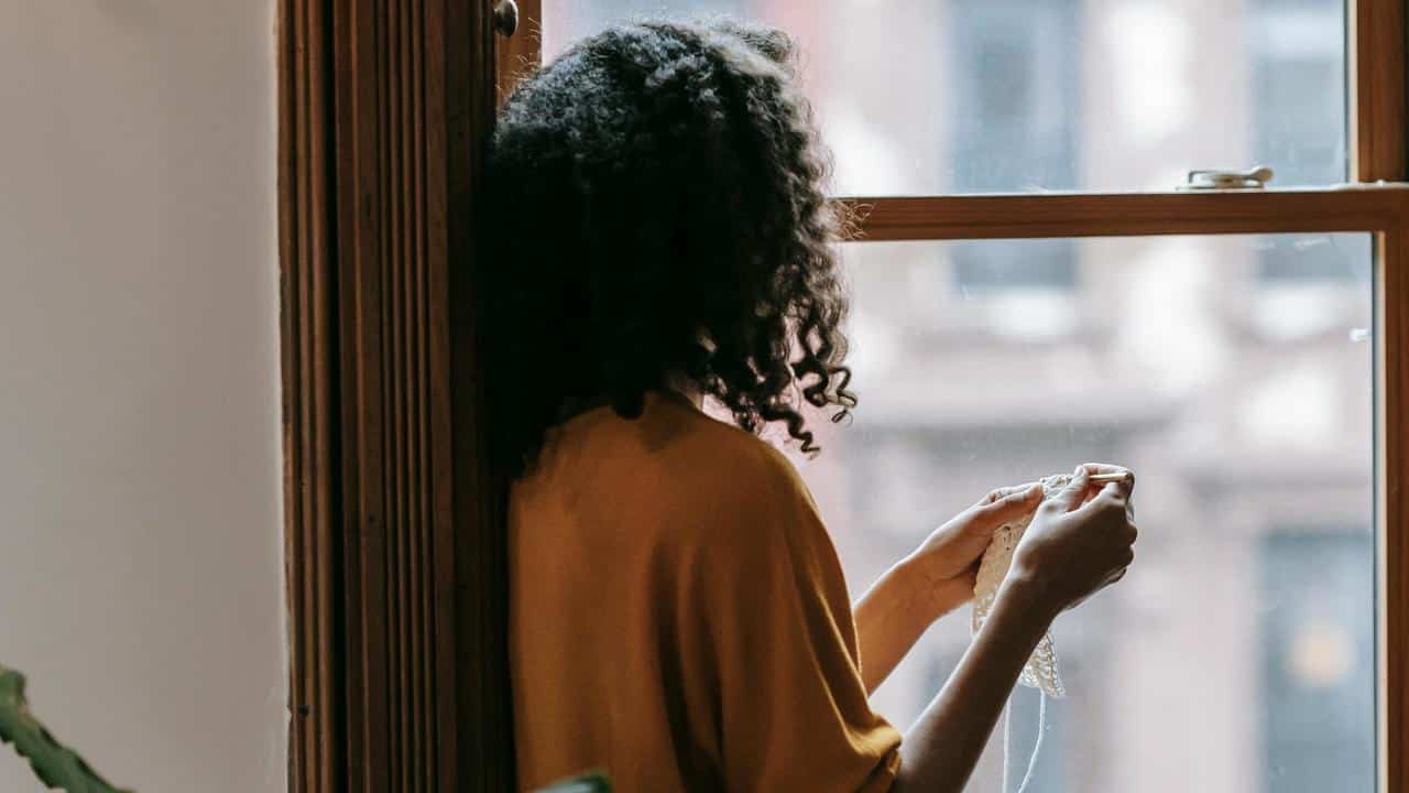 A person knitting by a window.