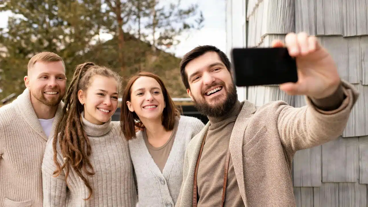 A group of friends smiling while taking a selfie outdoors.
